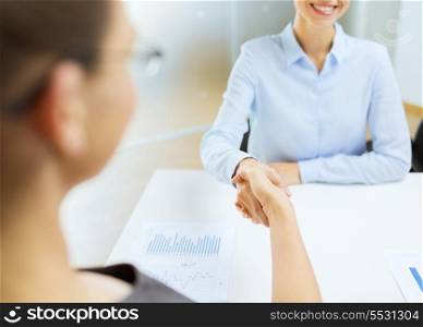 business and office concept - two smiling businesswoman shaking hands in office