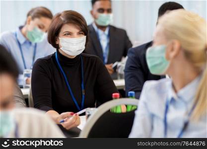 business and pandemic concept - group of people wearing face protective medical mask for protection from virus disease at international conference. business people in masks at conference
