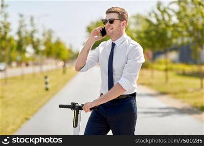 business and people and concept - young businessman calling on smartphone and electric scooter in city. businessman with scooter calling on smartphone