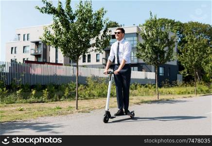 business and people and concept - young businessman riding electric scooter outdoors. young businessman riding electric scooter outdoors
