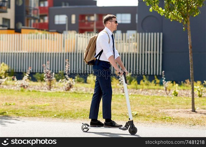business and people and concept - young businessman with backpack riding electric scooter. businessman with backpack riding electric scooter