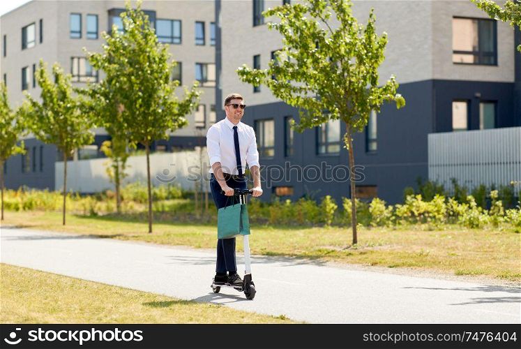 business and people and concept - young businessman with shopping bag riding electric scooter outdoors. businessman with shopping bag riding scooter