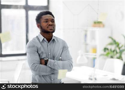 business and people concept - african american businessman looking at chart on glass board at office. businessman looking at glass board at office. businessman looking at glass board at office