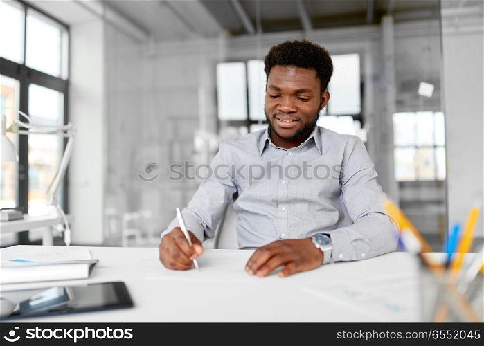 business and people concept - african american businessman with papers at office. african american businessman with papers at office. african american businessman with papers at office