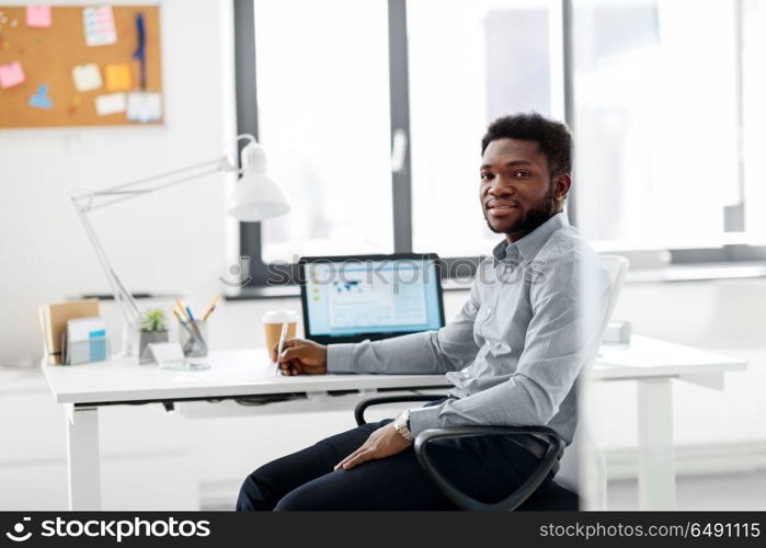 business and people concept - african american businessman with pen sitting at office table. african american businessman with pen at office. african american businessman with pen at office