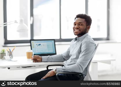 business and people concept - african american businessman with pen sitting at office table. african american businessman with pen at office. african american businessman with pen at office