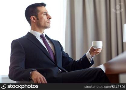 business and people concept - businessman drinking coffee at hotel room. businessman drinking coffee at hotel room