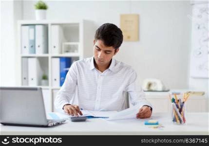 business and people concept - businessman with papers and calculator working at office. businessman with papers and calculator at office