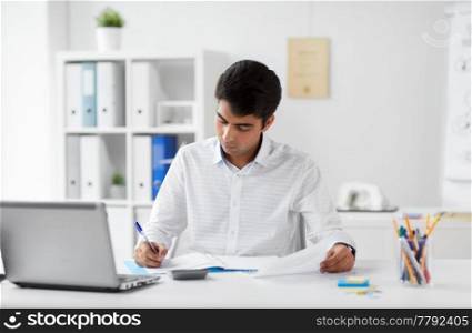 business and people concept - businessman with papers and laptop computer working at office. businessman working with papers at office