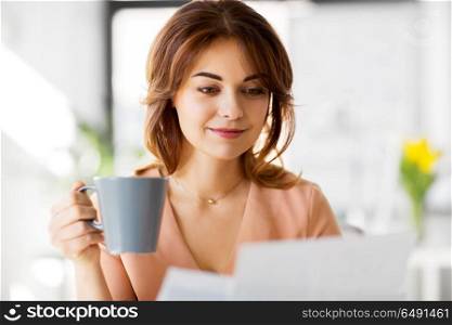 business and people concept - businesswoman drinking coffee and working at office. businesswoman with papers drinks coffee at office. businesswoman with papers drinks coffee at office