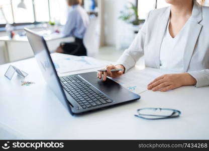 business and people concept - businesswoman with laptop computer and papers working at office. businesswoman with laptop working at office