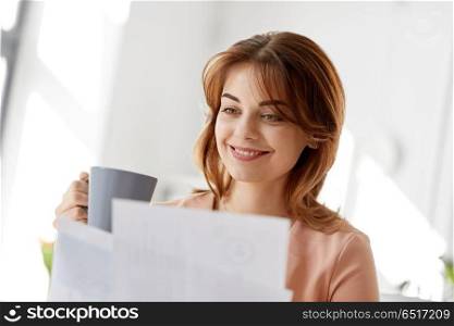 business and people concept - businesswoman with papers at working office and drinking coffee. businesswoman with papers drinks coffee at office. businesswoman with papers drinks coffee at office