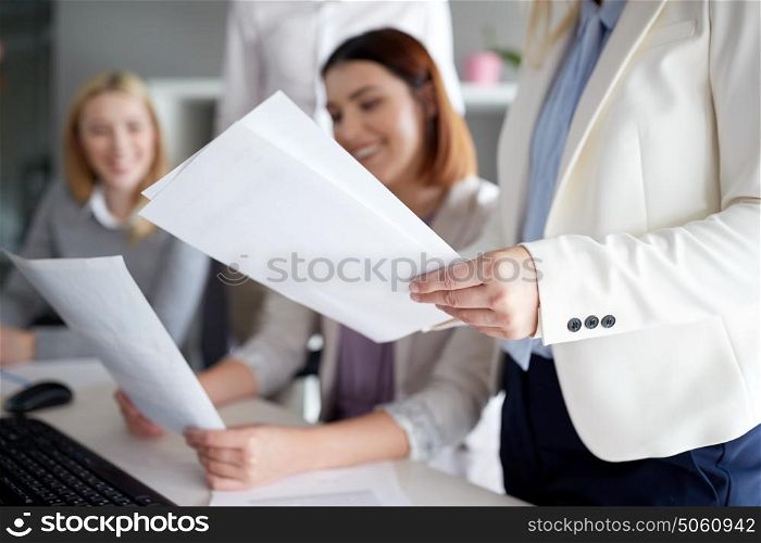 business and people concept - businesswomen with papers in office. businesswomen with papers in office