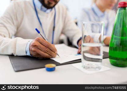 business and people concept - close up of businessman with papers and pen at international conference. businessman with papers at business conference