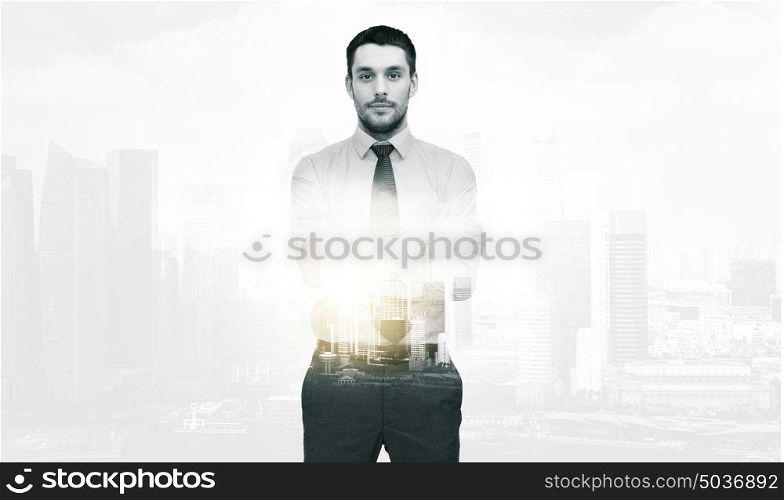 business and people concept - handsome businessman with crossed arms over city buildings and double exposure effect. handsome businessman with crossed arms