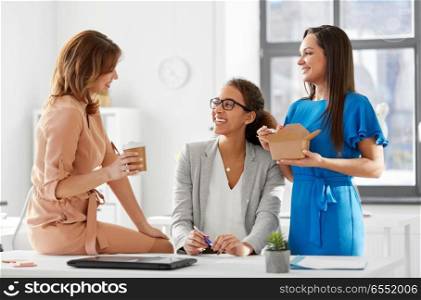 business and people concept - happy businesswomen having lunch or coffee break at office. businesswomen having lunch at office. businesswomen having lunch at office