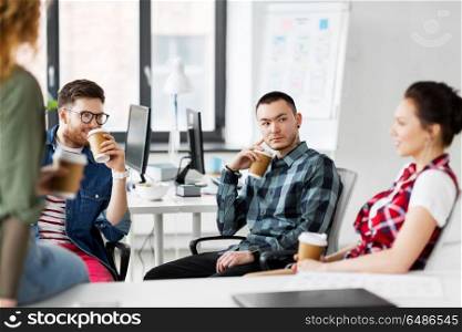 business and people concept - happy creative team drinking coffee at office. creative team drinking coffee at office. creative team drinking coffee at office