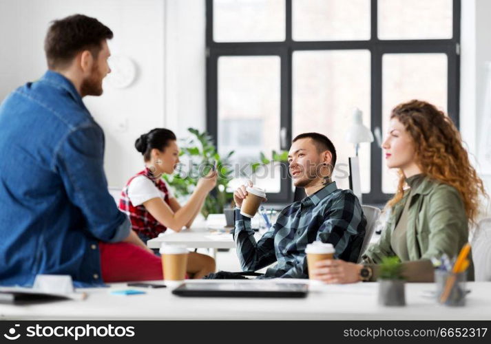 business and people concept - happy creative team drinking coffee at office. creative team drinking coffee at office