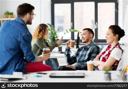 business and people concept - happy creative team drinking coffee at office. creative team drinking coffee at office