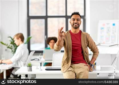 business and people concept - happy smiling indian man showing ok hand sign at office. smiling indian man showing ok hand sign at office. smiling indian man showing ok hand sign at office