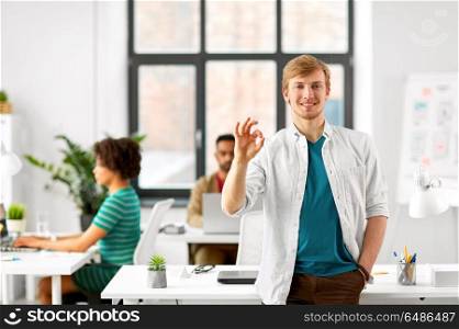 business and people concept - happy smiling man showing ok hand sign at office. happy smiling man showing ok hand sign at office. happy smiling man showing ok hand sign at office