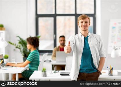 business and people concept - happy smiling man showing thumbs up at office. happy smiling man at office. happy smiling man at office