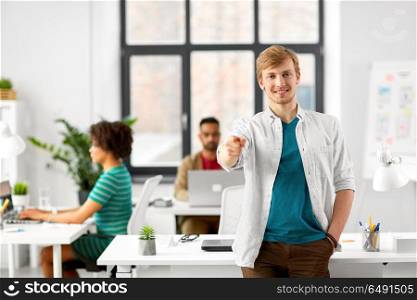 business and people concept - happy smiling man with pointing finger at you at office. happy smiling man pointing finger at you at office. happy smiling man pointing finger at you at office