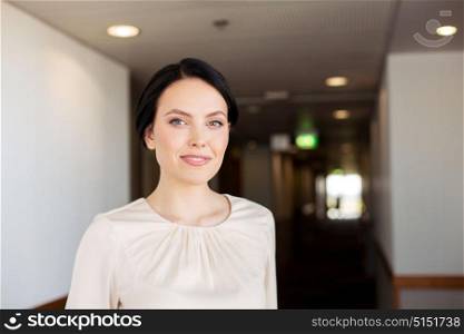 business and people concept - happy woman at corridor in hotel. happy woman at corridor in hotel