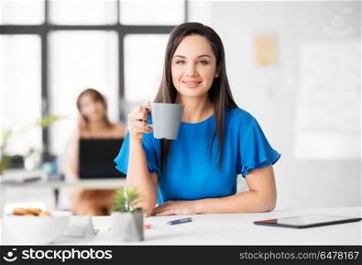 business and people concept - happy young businesswoman drinking coffee at office. happy businesswoman drinking coffee at office. happy businesswoman drinking coffee at office