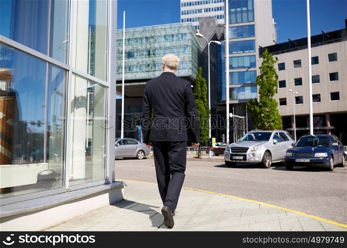 business and people concept - senior businessman walking along city street. senior businessman walking along city street