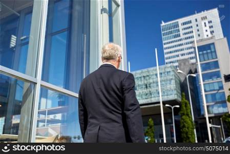 business and people concept - senior businessman walking along city street. senior businessman walking along city street