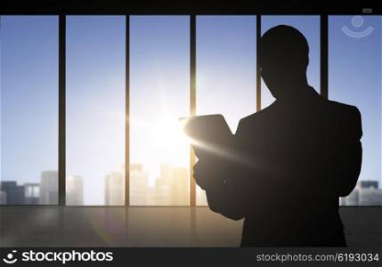 business and people concept - silhouette of business man with tablet pc over office window background. silhouette of businessman with tablet pc at office