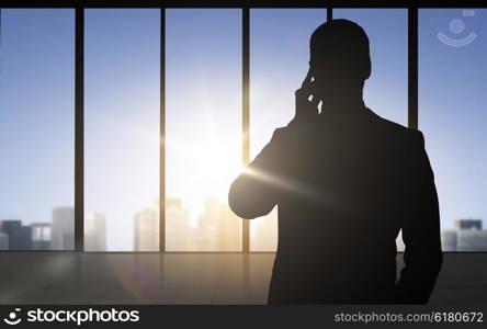 business and people concept - silhouette of businessman calling on smartphone over office window background. silhouette of business man calling on smartphone