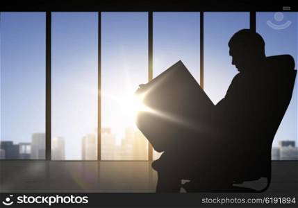 business and people concept - silhouette of businessman reading documents over office window background. silhouette of businessman reading documents