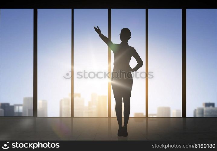 business and people concept - silhouette of woman pointing hand and showing direction over office window background. silhouette of business woman pointing hand