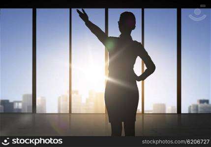 business and people concept - silhouette of woman pointing hand and showing direction over office window background. silhouette of business woman pointing hand