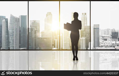 business and people concept - silhouette of woman with folders over office window and singapore city skyscrapers background and sun light. silhouette of business woman with folders