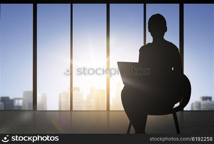 business and people concept - silhouette of woman with laptop sitting on chair over office window background. silhouette of business woman with laptop