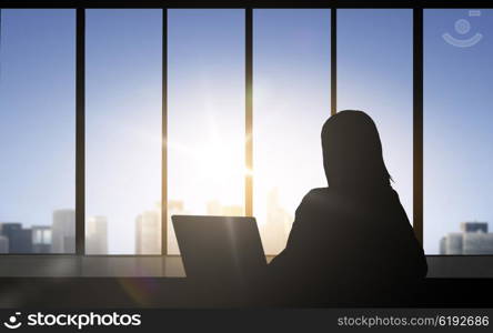 business and people concept - silhouette of woman with laptop sitting over office window background. silhouette of business woman with laptop
