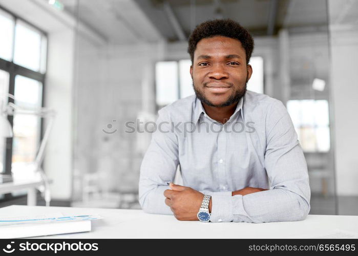 business and people concept - smiling african american businessman at office. smiling african american businessman at office