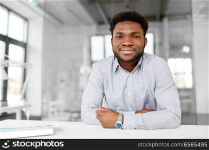 business and people concept - smiling african american businessman at office. smiling african american businessman at office