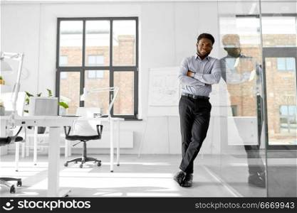 business and people concept - smiling african american businessman at office glass wall. smiling african american businessman at office. smiling african american businessman at office
