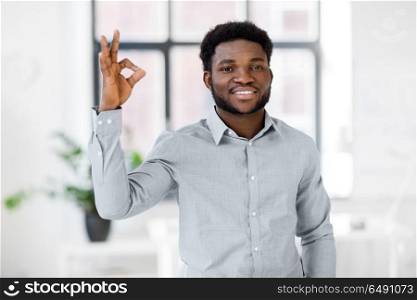 business and people concept - smiling african american businessman at office showing ok hand sign. african american businessman at office showing ok. african american businessman at office showing ok