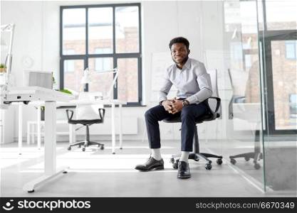 business and people concept - smiling african american businessman sitting on office chair. african businessman sitting on office chair. african businessman sitting on office chair