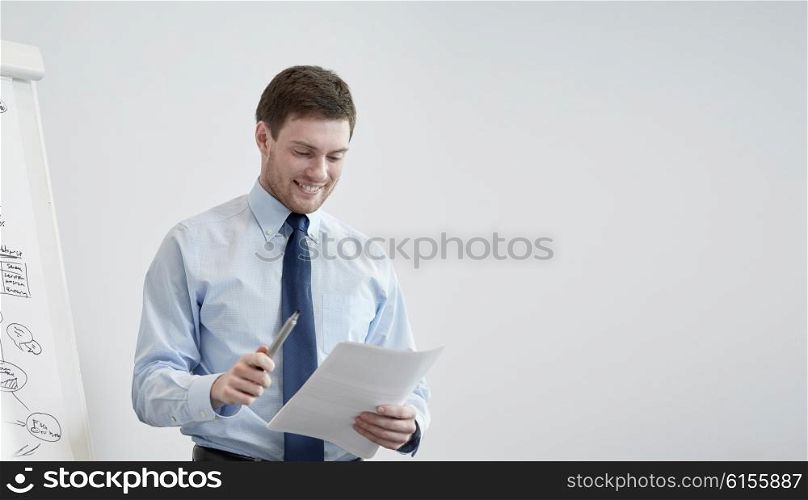 business and people concept - smiling businessman on presentation in office. smiling businessman on presentation in office