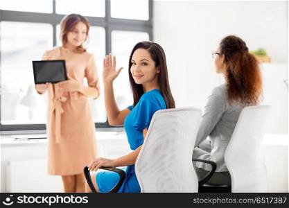 business and people concept - smiling businesswoman waving hand at meeting in office. businesswoman waving hand at meeting in office. businesswoman waving hand at meeting in office