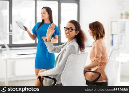 business and people concept - smiling businesswoman waving hand at meeting in office. businesswoman waving hand at meeting in office. businesswoman waving hand at meeting in office