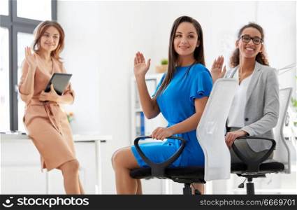 business and people concept - smiling businesswomen waving hands at meeting in office. businesswomen waving hands at meeting in office. businesswomen waving hands at meeting in office