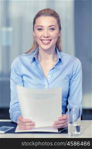 business and people concept - smiling woman holding papers in office. smiling woman holding papers in office