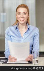 business and people concept - smiling woman holding papers in office
